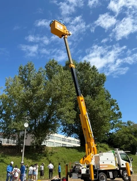 青空へ伸びる高所作業車。バケットに乗って上がる体験
