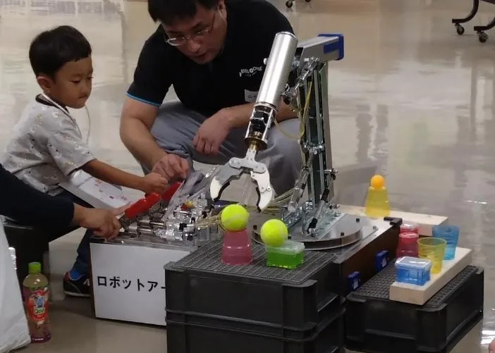 ロボットアームを操作する体験のようす(過去の実演風景)